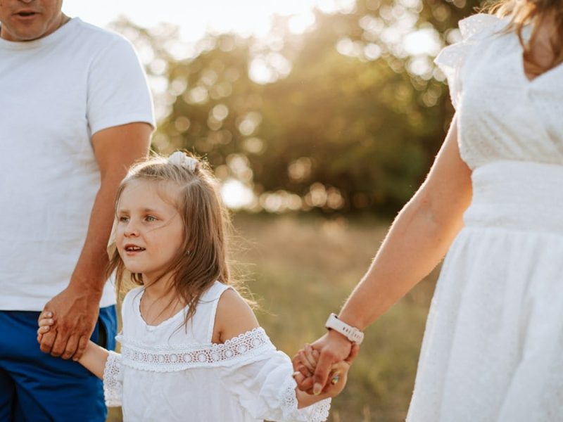 A man and a woman holding hands with a little girl